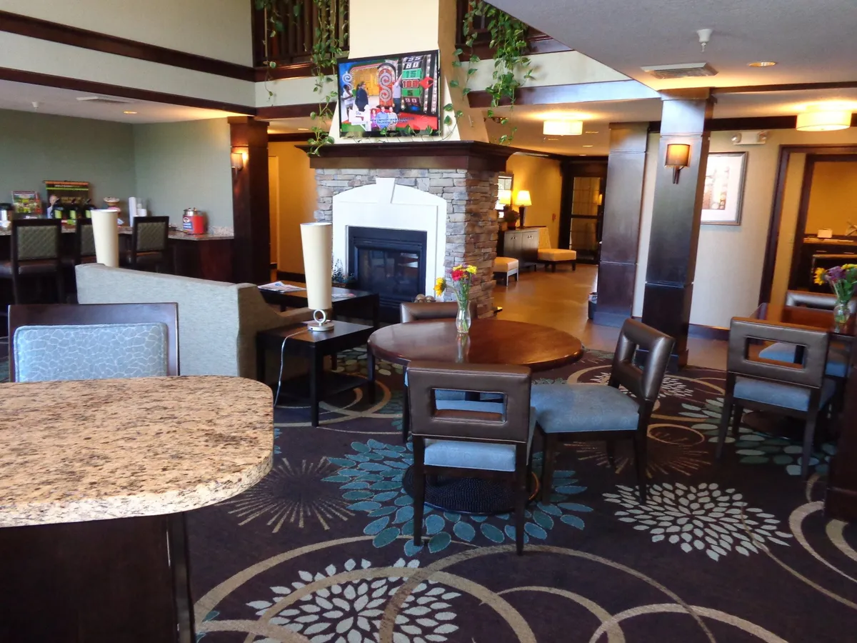 This image showcases a warm, inviting living space centered around a fireplace. A coffee table with fresh flowers and tasteful artwork on the walls add to the cozy atmosphere. The arrangement of comfortable seating makes it ideal for conversation and socializing, while soft lighting and decor create a welcoming mood.